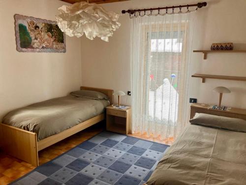 a bedroom with two beds and a window at Baita Azzurro in Isolaccia