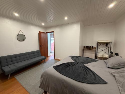 a bedroom with a bed and a couch in it at Casa de Santo Amaro in Ribeirinha