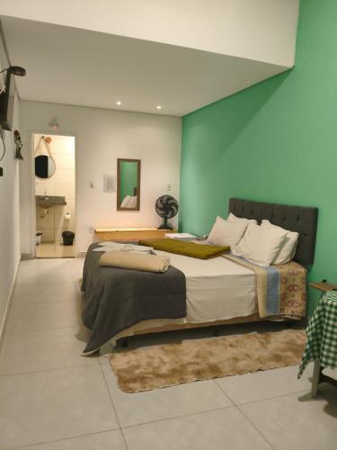 a bedroom with a large bed and a green wall at Pousada Alforria Lavras Novas centro in Lavras Novas
