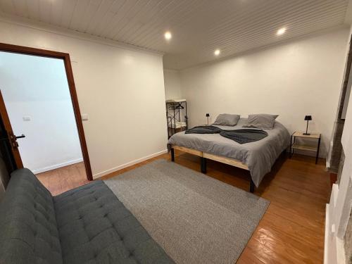a bedroom with a bed and a couch at Casa de Santo Amaro in Ribeirinha
