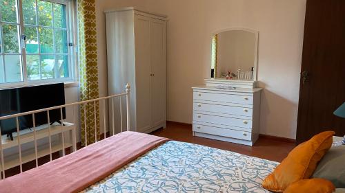 a bedroom with a bed and a dresser with a mirror at The Lemon Tree House in Quinta do Conde