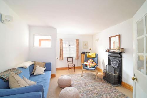 a living room with a blue couch and a fireplace at Beautiful Cottage & Garden Quantock Hills in Nether Stowey