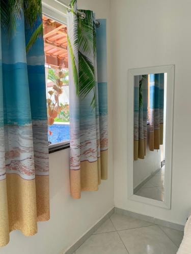 a mirror and curtains in a room with a window at Villa Paradise in Brazil - Praia de Guaratiba Prado-BA in Prado