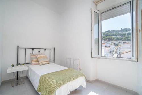 a white bedroom with a bed and a window at EDIFICI ROSA- Ático primera línea in Port de la Selva