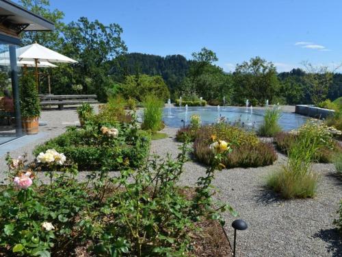 a garden with flowers and a pond in the background at Apartment Sunnebad Sternenberg by Interhome in Sternenberg