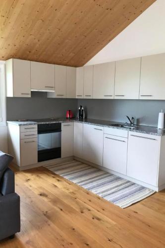 a kitchen with white cabinets and a wooden ceiling at Apartment Ballmoos Ferienwohnung by Interhome in Gais