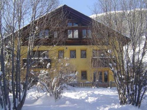 a yellow house with snow in front of it at Apartment Chesa Engel by Interhome in La Punt-Chamues-ch