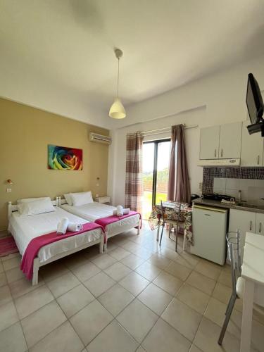 a bedroom with a large bed and a kitchen at Green Garden Studios in Koskinou