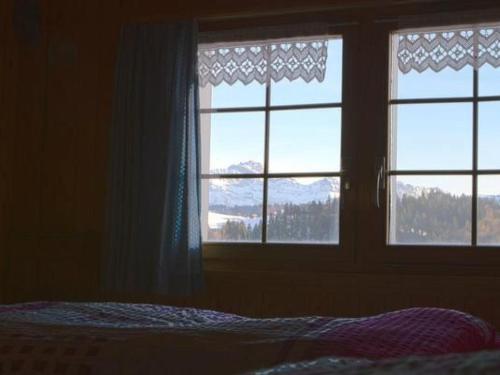 a bedroom with two windows and a bed with a view at Apartment Hasenbüel by Interhome in Ricken