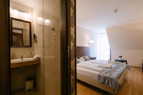 a bedroom with a bed and a sink and a shower at Petrény Borpanzió in Egerszalók