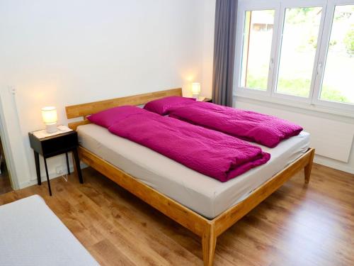 a bed with a purple blanket on it in a room at Apartment Panoramablick by Interhome in Nesslau