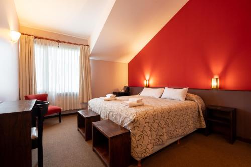 ein Hotelzimmer mit einem Bett und einer roten Wand in der Unterkunft Pudu Lodge in El Chalten
