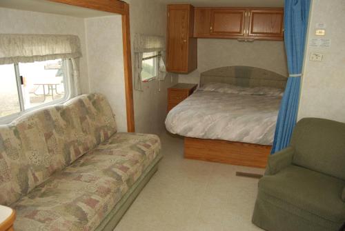 a bedroom with a bed and a couch and a chair at Crescent Bar Camping Resort Studio Cabin 2 in Trinidad