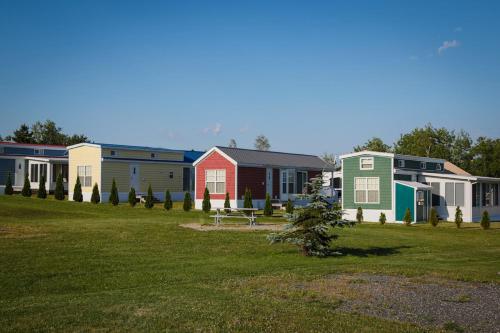 una fila de casas coloridas en un campo de hierba en Narrows Too Camping Resort Loft Cottage 12 en Trenton