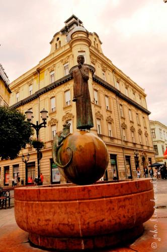 a statue of a woman sitting on a fountain in front of a building at Buda Panzió in Győr
