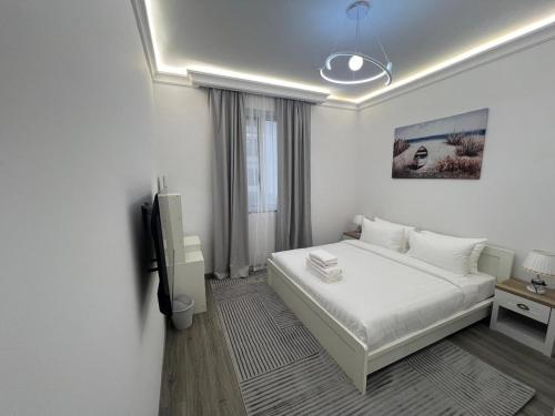 a white bedroom with a bed and a tv at Nasma Homes Al Dana in Abu Dhabi