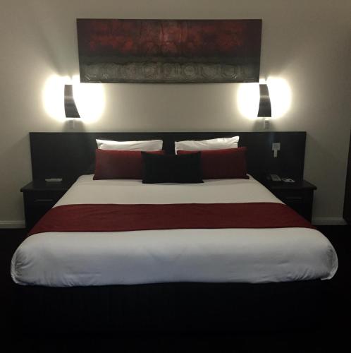 a bedroom with a large bed with red pillows at Abel Tasman Motor Inn in Dubbo