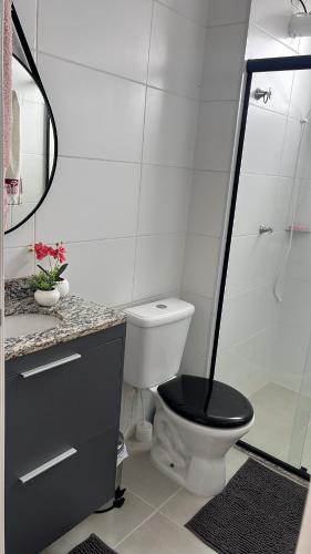 a bathroom with a toilet with a black seat at Doce lar in Pouso Alegre