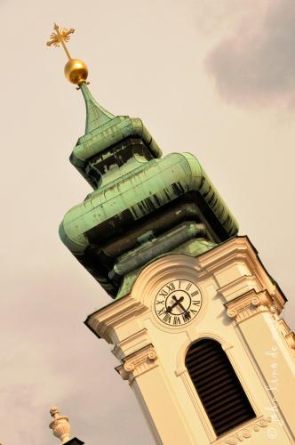 a clock tower with a cross on top of it at Buda Panzió in Győr