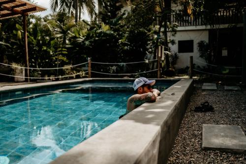 a young boy sitting next to a swimming pool at Casa Chapolin Boutique Guesthouse in Palomino