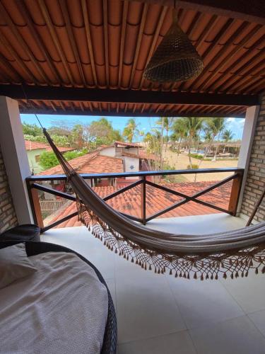 a hammock in a room with a view of a house at Recanto da Praia Pousada in São Miguel do Gostoso