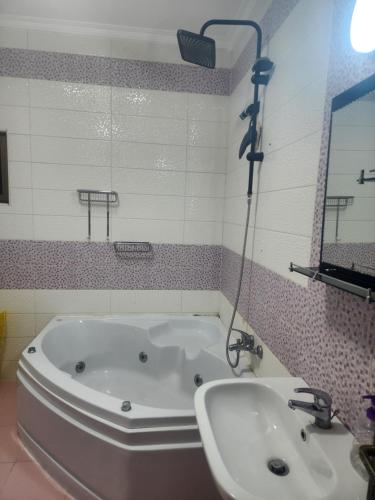 a bathroom with a tub and a sink and a mirror at A big Family nice sunset flat in Amman
