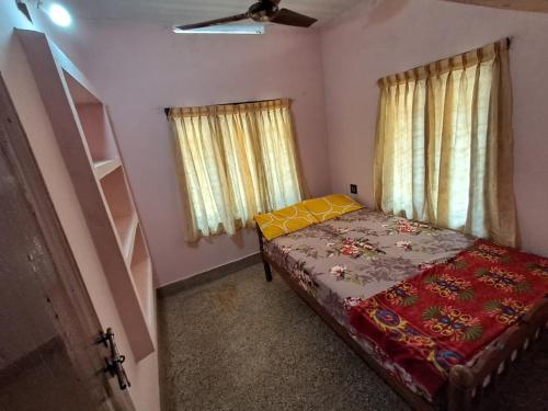 a small bedroom with a bed and two windows at A-Kutty in Irinjālakuda