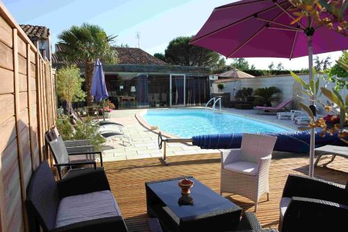 una piscina con sillas y una sombrilla púrpura en Chambres d'Hôtes Le Logis du Port Paradis, en Nieulle-sur-Seudre