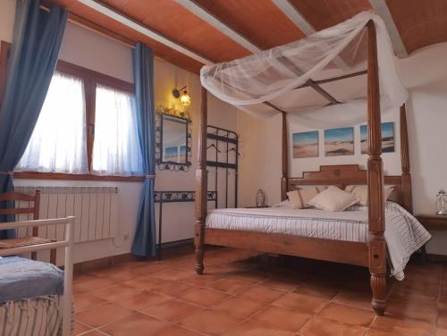 a bedroom with a four poster bed and a window at Masía Can Janàs in Lliçà d'Amunt