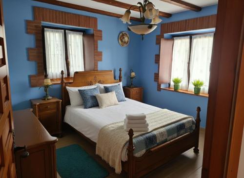 a bedroom with a bed with blue walls and windows at El BurbyI in Somo