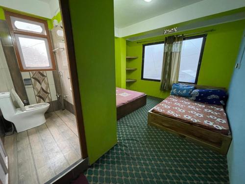 a green room with two beds and a toilet at Yolmo Hotel in Gorkhe