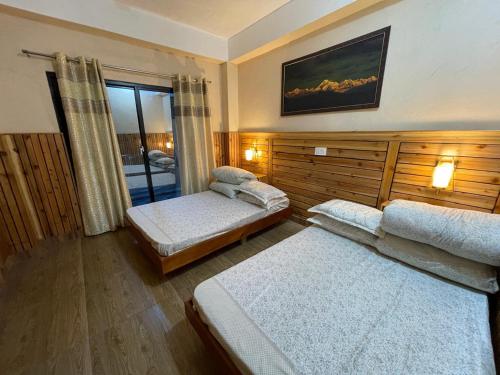 a bedroom with two beds and a window in it at Yolmo Hotel in Gorkhe