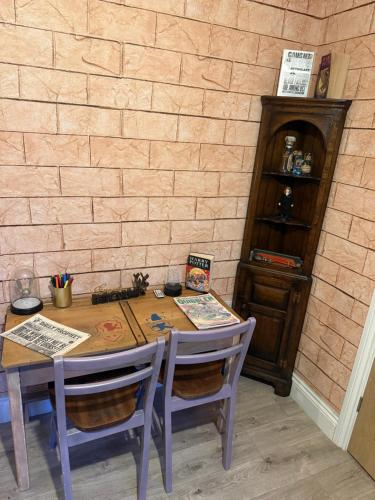 a wooden table with chairs and a book shelf at Potters Hideout- 2 Bedroom 2 Bathroom Apartment in Watford