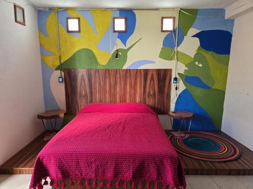 a bedroom with a pink bed with a colorful wall at Casa del Árbol Xochimilco in Oaxaca City
