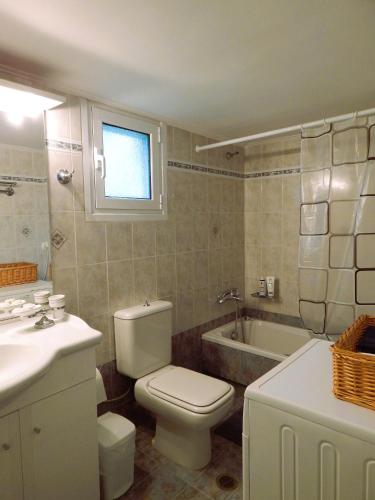 a bathroom with a toilet and a sink and a tub at Menelais Guesthouse in Khotoússa