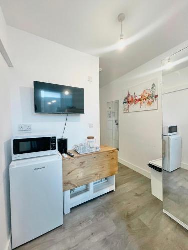 a room with a refrigerator and a tv on the wall at Rooms in Kings Cross in London