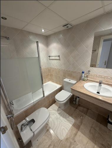 a bathroom with a toilet and a sink and a tub at Casa Ricardo Penthouse in Sitio de Calahonda