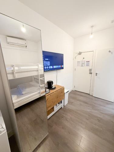 a large white room with a refrigerator and a desk at Rooms in Kings Cross in London