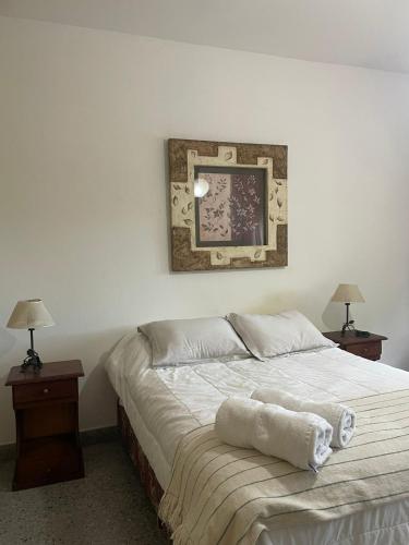 a bed in a bedroom with two lamps and a picture at EL RELOJ in Chascomús