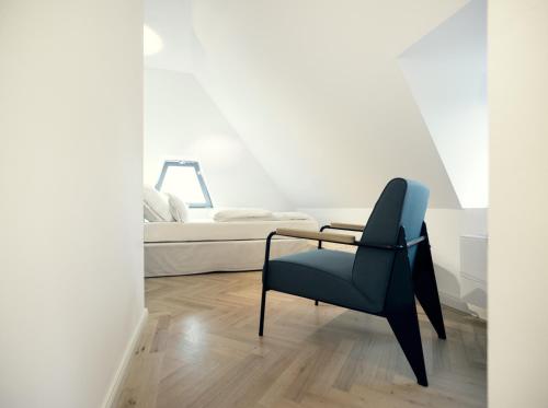 a bedroom with a blue chair and a bed at THE QVEST hideaway in Cologne