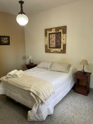 a bedroom with a large white bed and two tables at EL RELOJ in Chascomús
