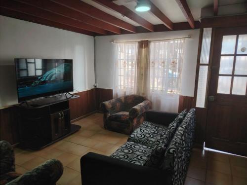 a living room with couches and a flat screen tv at Iquique Backpackers Beach House in Iquique