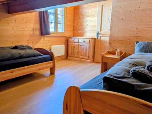 a bedroom with two beds in a log cabin at Maisonette-Wohnung in Rueras bei Sedrun - 200m zum Bahnhof - Perfekt für Ski & Ausflüge in Rueras