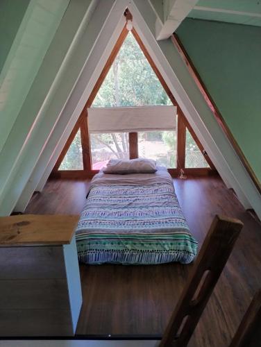 a bed sitting in the middle of a loft at Mini cabaña in Pucón