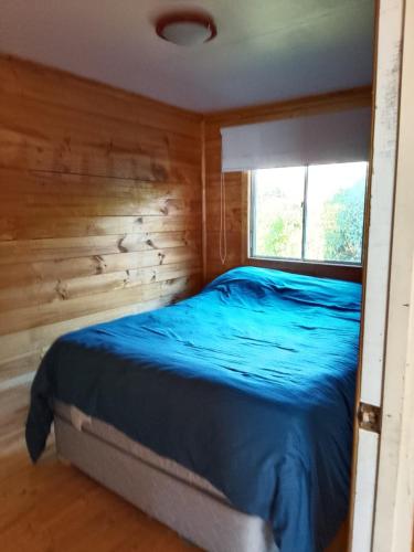 a bed in a wooden room with a window at Cabaña tree in Boca Pupuya