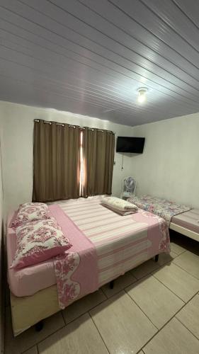 a bedroom with two beds and a flat screen tv at Suites da Bela 01 Caparaó in Caparaó Velho