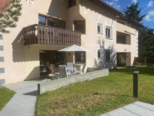 a house with a patio with an umbrella and chairs at Apartment Sassella 2a by Interhome in La Punt-Chamues-ch