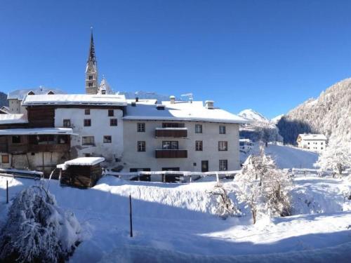 a building covered in snow in front of a mountain at Apartment Chasa Jaro by Interhome in Santa Maria Val Müstair