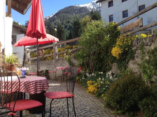 a table and chairs with a red umbrella on a patio at Apartment Chasa Jaro by Interhome in Santa Maria Val Müstair