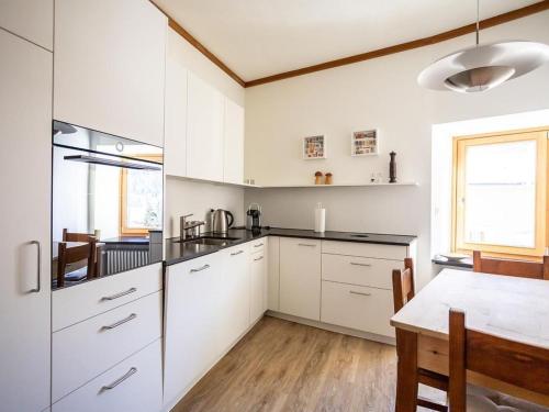 a kitchen with white cabinets and a wooden table at Apartment Chesa Müller by Interhome in Zuoz